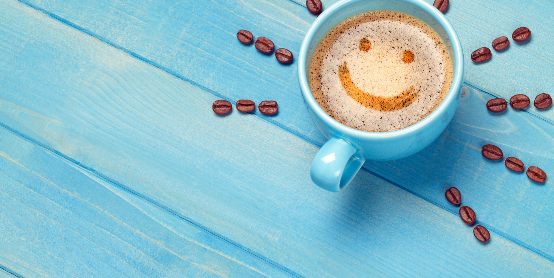 Coffee cup with smiley face on blue wooden table